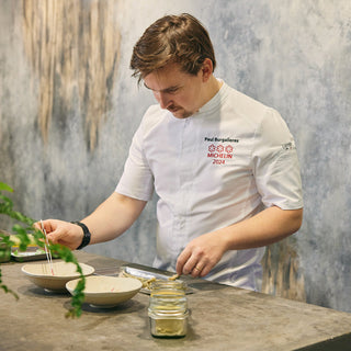 Michelin chef works in the kitchen wearing a white, short-sleeve men's chef coat with a mandarin collar and a front pocket.
